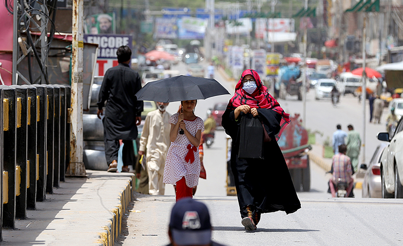 A girl on the way under cover of an umbrella to protect herself from direct sunlight during a hot weather at Ghouri Town
