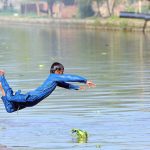A youngster jumping and bathing in the canal to get relief from the hot weather in the city