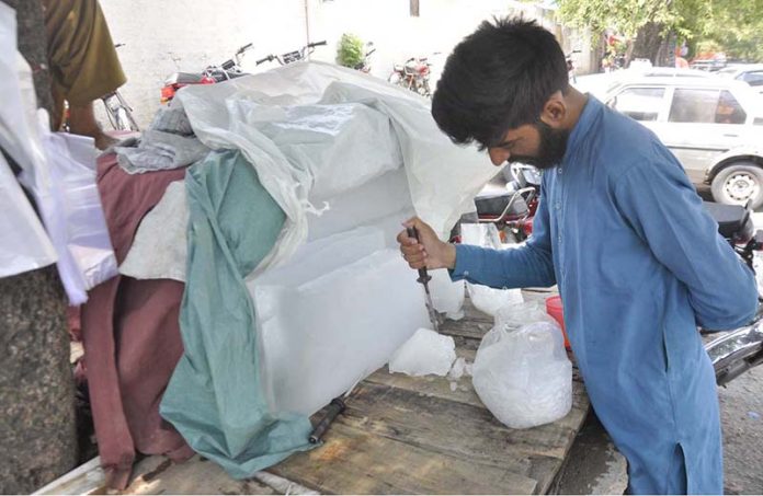 A vendor is cutting ice block into pieces to sell at Rice Canal Road