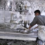 A worker busy in cutting marble with machine at local marble factory