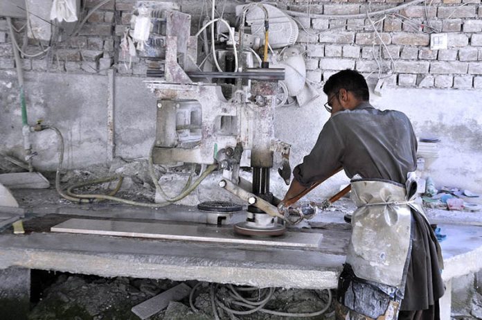 A worker busy in cutting marble with machine at local marble factory