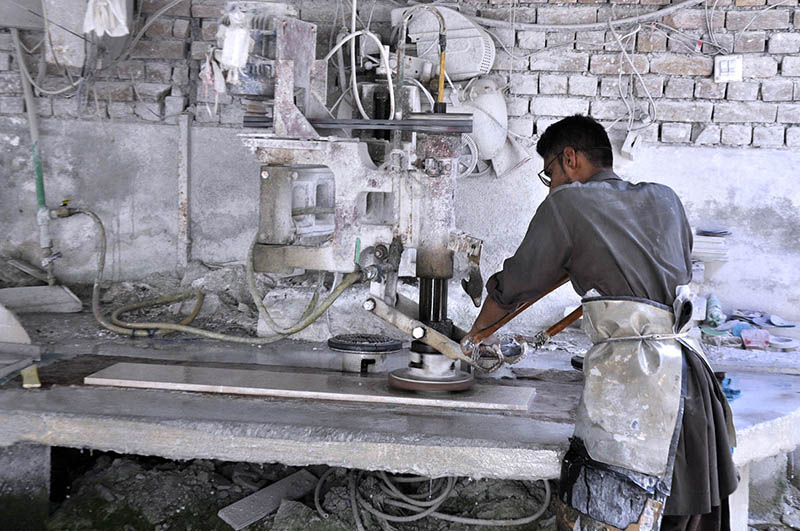 A worker busy in cutting marble with machine at local marble factory