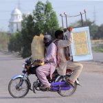 A bike rider holding room cooler heading towards his destination