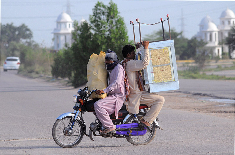 A bike rider holding room cooler heading towards his destination