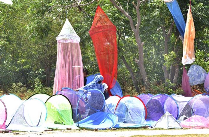 A woman purchasing mosquito net at a vendors roadside setup