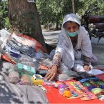 A female vendor selling various religious items on the side of the I-10 Markaz Road