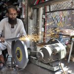 A blacksmith is sharpening knives and axes at his work-place to sell them to the butchers for using them to slaughter sacrificial animals during Eid-ul-Azha
