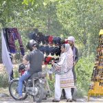 A woman purchasing sun glasses at a vendors roadside setup