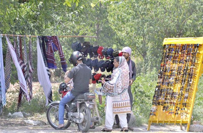 A woman purchasing sun glasses at a vendors roadside setup