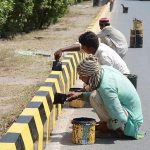 Painters are painting sidelines of a Jhumra Road during maintenance work in the city