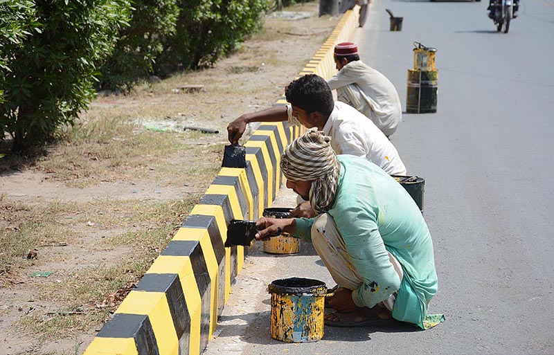 Painters are painting sidelines of a Jhumra Road during maintenance work in the city