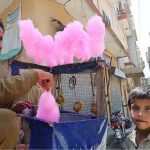 A vendor preparing cotton candy for a young boy at Pirwadhai