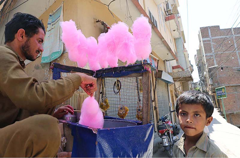 A vendor preparing cotton candy for a young boy at Pirwadhai