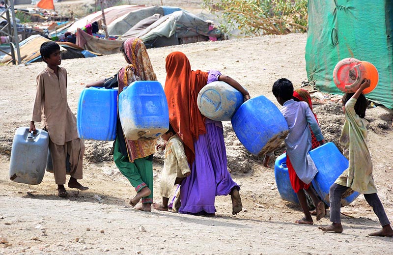 Gypsy children on the way while carrying water canes for filling clean water at Qasimabad