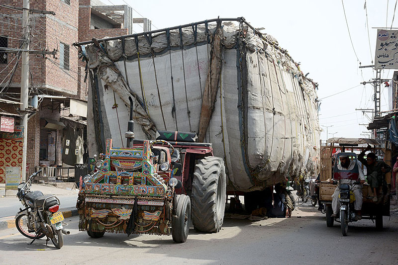 An over loaded tractor trolley parked on busy Millat Road creating hurdles in smooth flow of traffic and needs the attention of concerned authorities