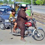 A youngster carrying sacrificial animal (goat) while sitting on rear seat of motorcycle after purchasing from Cattle Market