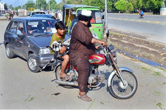 A youngster carrying sacrificial animal (goat) while sitting on rear seat of motorcycle after purchasing from Cattle Market