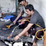 Vendors cleaning sacrificial animal trotters (Paya) for customers on the 2nd day of Eid Ul Azha at their workplace