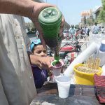 A street vendor preparing traditional sweet stuff known as 'Gola' for a customer at Liaquat Bagh