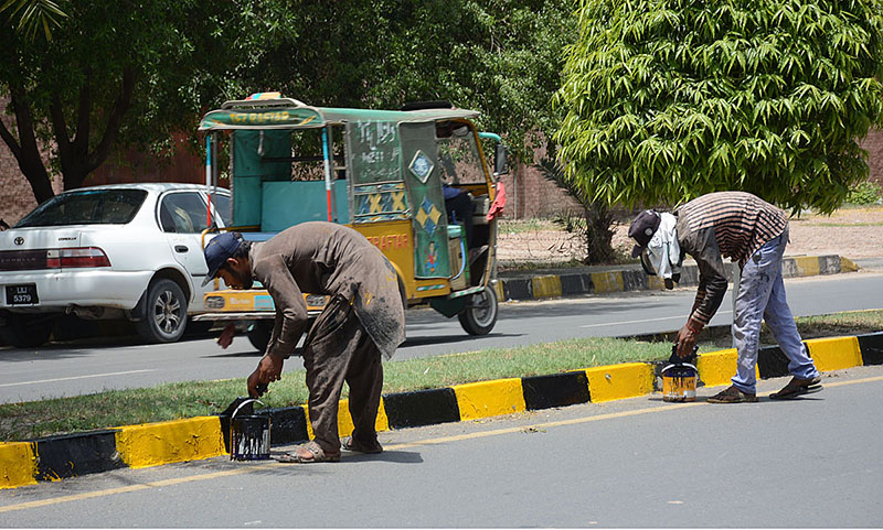 Workers are painting sidelines of a University Road during maintenance work in the city