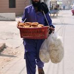 A street vendor selling edible items while shuttling on the road