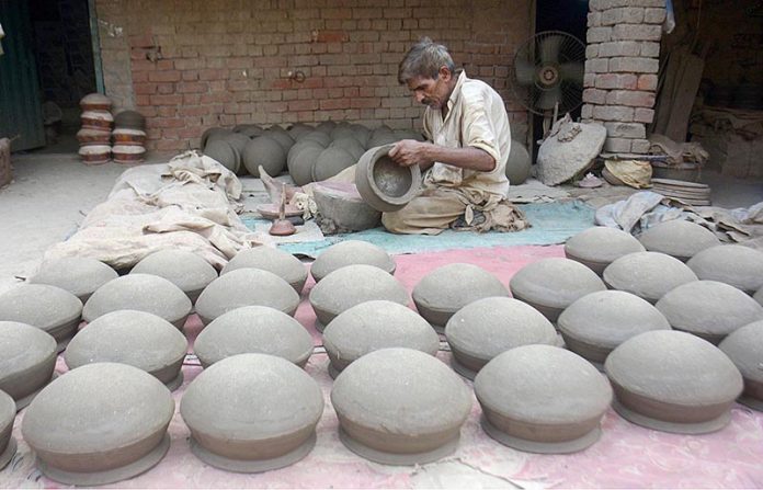 A potter is making traditional clay pots from clay in his workshop at the Kanchi Stop Area