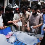 A throng of people purchasing ice from a roadside vendor during a scorching weather in the twin cities