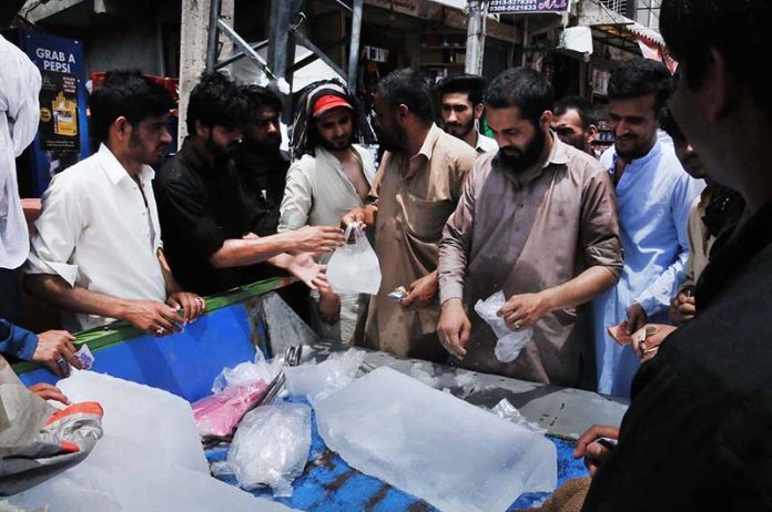 A throng of people purchasing ice from a roadside vendor during a scorching weather in the twin cities