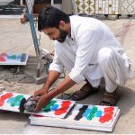 A worker busy in cutting marble with the help of a machine at his workplace