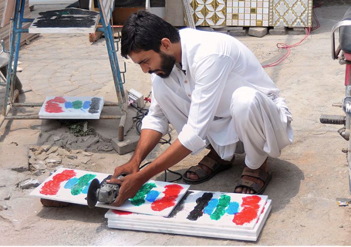 A worker busy in cutting marble with the help of a machine at his workplace