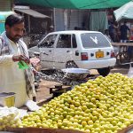 Vendor is busy in sprinkling water on the lemon to keep them fresh at his roadside setup