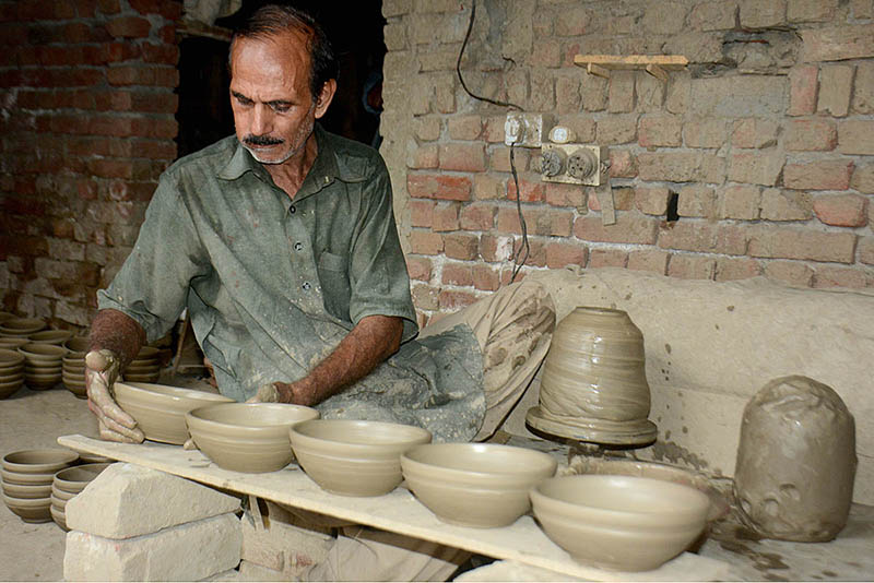 A potter is making traditional clay pots from clay in his workshop at the Kanchi Stop Area