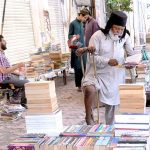 An elderly disabled person selecting books from roadside old books stall in Provincial Capita