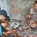 Skilled persons make brass and copper metal pots in traditional way at their work place