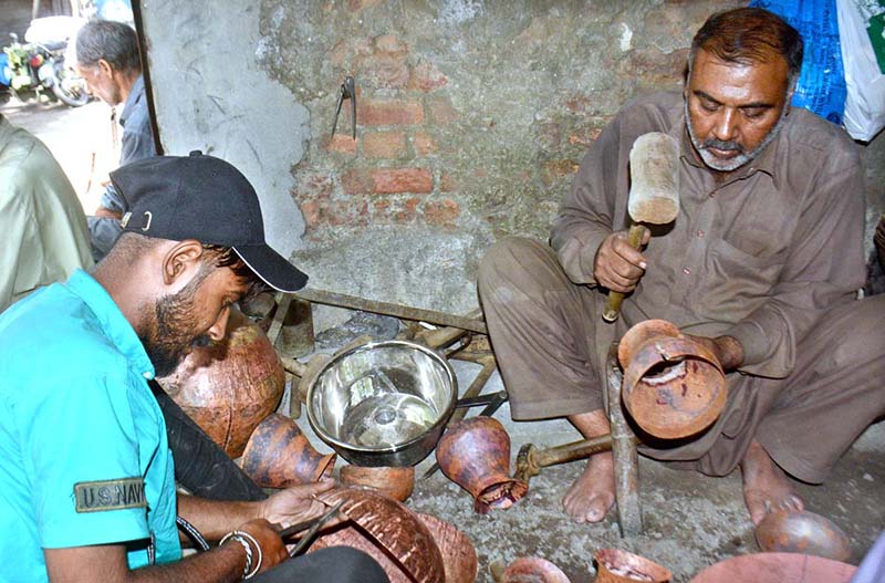 Skilled persons make brass and copper metal pots in traditional way at their work place