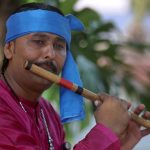 Artist plays his musical instrument flute to attract people during Saqafati Mela at Lok Virsa