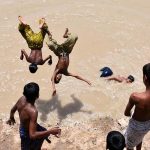 Youngsters jumping into the canal to beat the heat during hot weather in the city