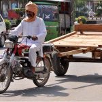 A motorcycle cart holder heading towards his destination at College road