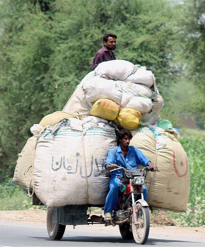 A person riding an overloaded tricycle rickshaw which may cause any mishap