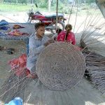 A worker busy in making traditional basket with branches of tree