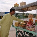 A vendor displaying traditional handmade items at his roadside setup to attract the customers