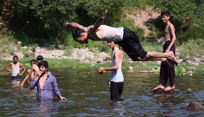 Youngsters enjoy jumping and bathing in the Rawal dam adjacent Nallah during a hot day in the Federal Capital