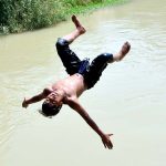 A youngster dive into a water canal to get some relief from hot weather in the city