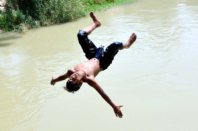 A youngster dive into a water canal to get some relief from hot weather in the city