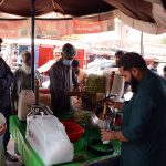 A vendor selling traditional summer drink (Shikanjabeen) to attract the customers at his roadside setup during hot weather.