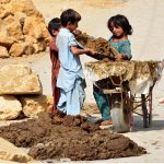 Children busy in loading dung in the handcart for prepare the dung cakes at Latifabad