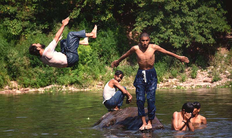 Youngsters enjoy jumping and bathing in the Rawal dam adjacent Nallah during a hot day in the Federal Capital