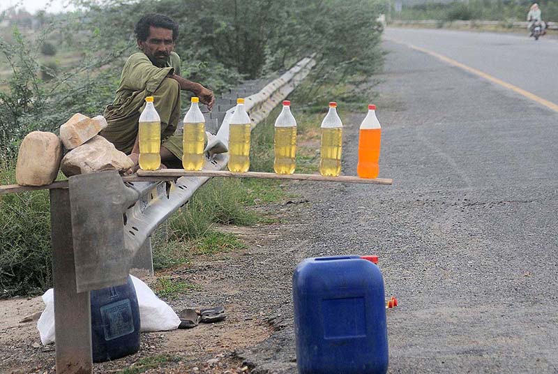 A tri-cycle delivery cart holder purchasing fuel from an illegal petrol selling point along the roadside setup needs the attention of concerned authorities