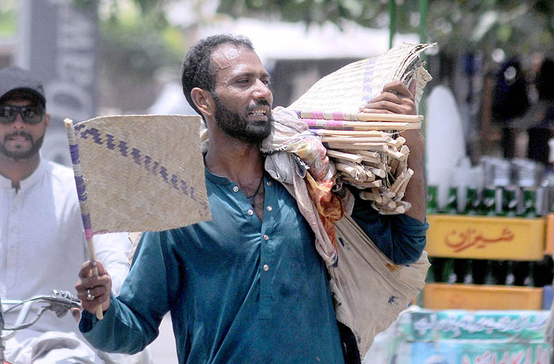 A street hawker selling handmade fans while shuttling on Hussain Agahi Road