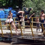 Youngsters jumping and bathing in the canal to get relief from the hot weather in the city